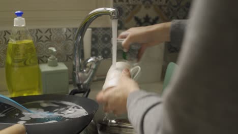 close up of hands washing a mug with a sponge