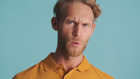 Unpleasant young bearded man in polo T-shirt in studio