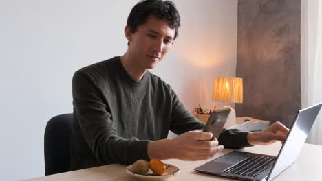 Man-working-on-his-computer-receives-a-text-message-that-makes-him-smile