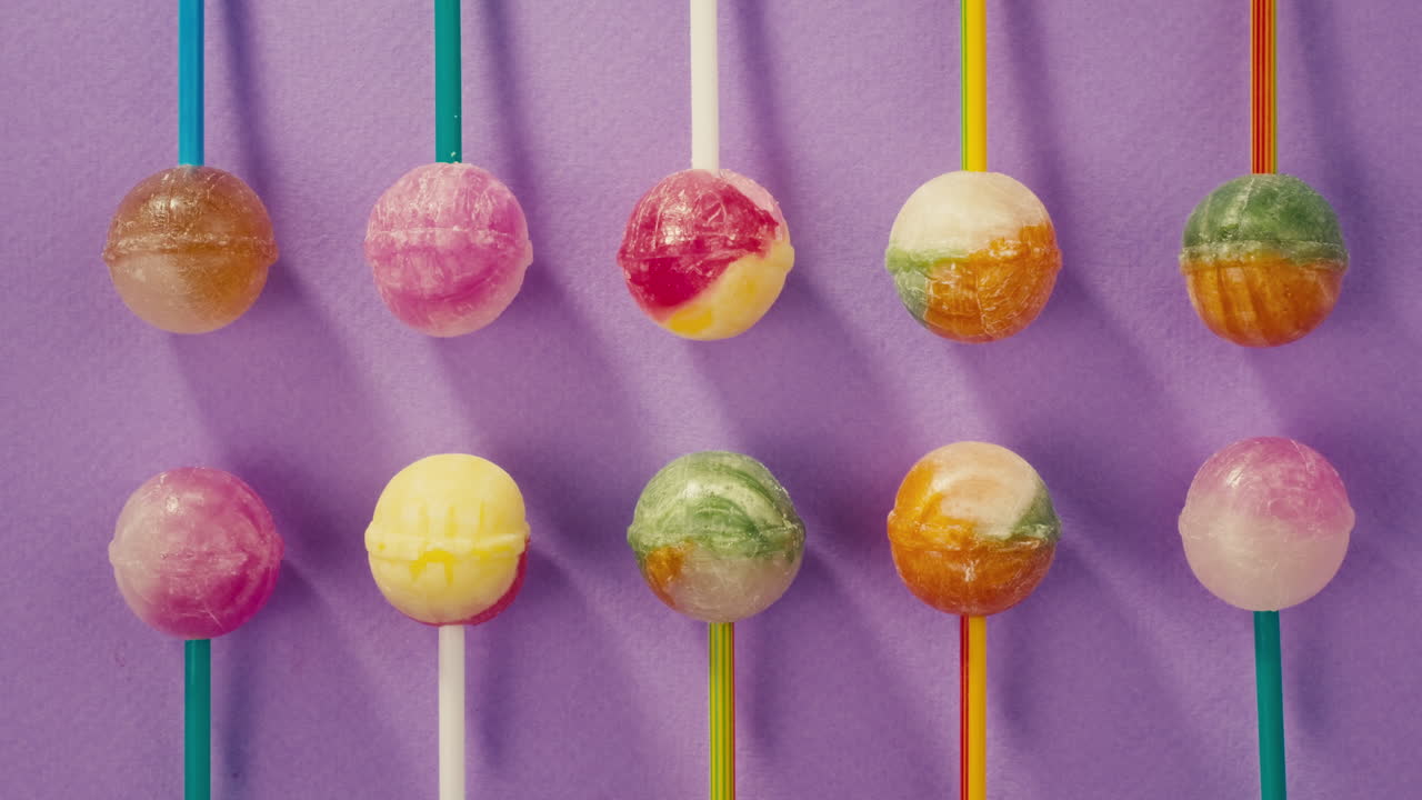 Sweet lollipops on color purple background zoom frame . Bright texture sugar candies close up top view. Composition of favorite children&#x27;s summer sweets. Studio shot for shop, supermarket, confectionery
