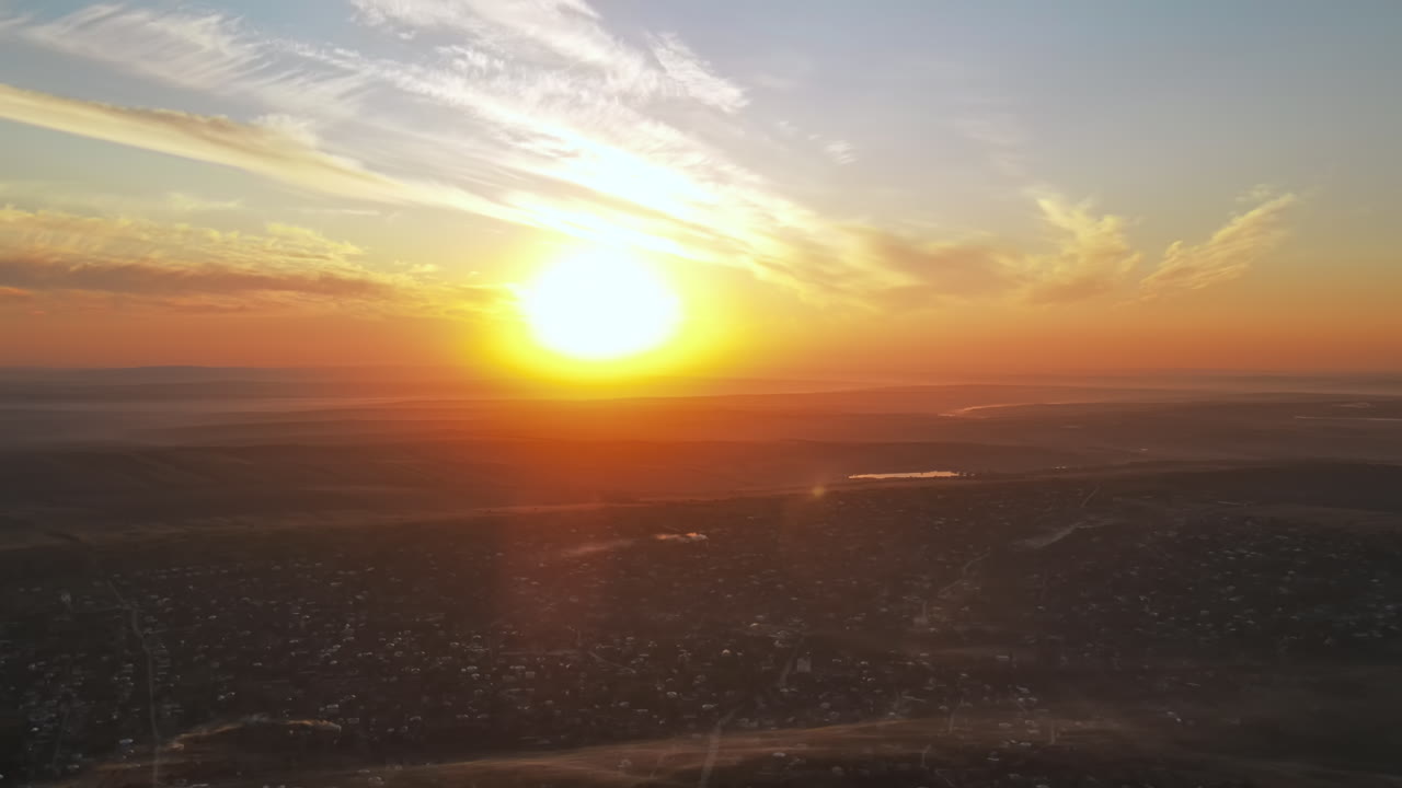 Aerial drone view of village in Moldova at sunset. Few columns of smoke from fires, wide fields