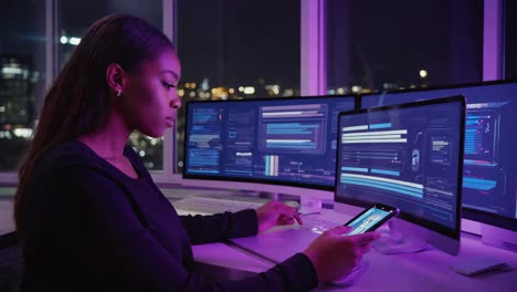 woman working with multiple monitors and smartphone at night in a modern office