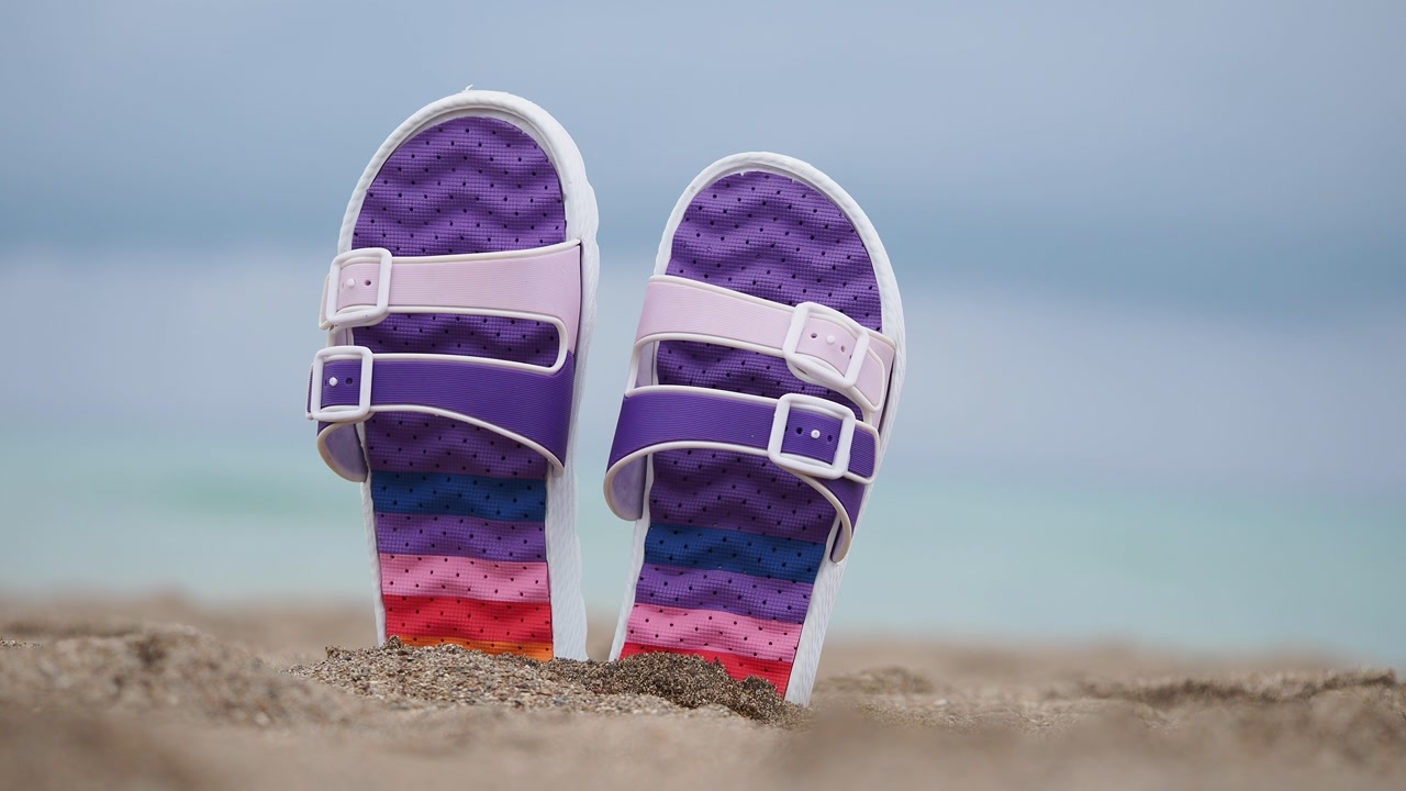 Colorful Sandals on a Sandy Beach with the Ocean in the Background