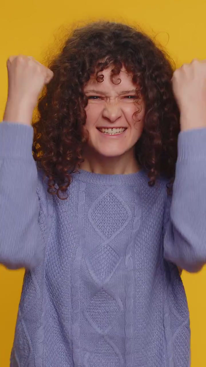 Donna elegante in maglione che urla, alzando i pugni in segno di "ce l'ho fatta", celebrando il successo e la vittoria.