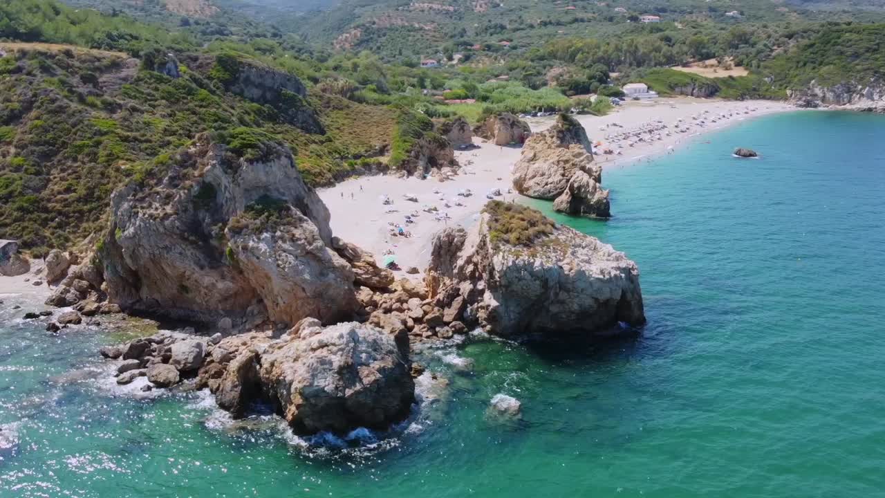 Ripresa cinematica con drone delle iconiche rocce giganti sulla spiaggia di Potistika nel Pelio. Vista dall'alto delle acque turchesi dell'Egeo, sabbia dorata e lussureggianti colline verdi. Ideale per promozioni di viaggi e turismo.
