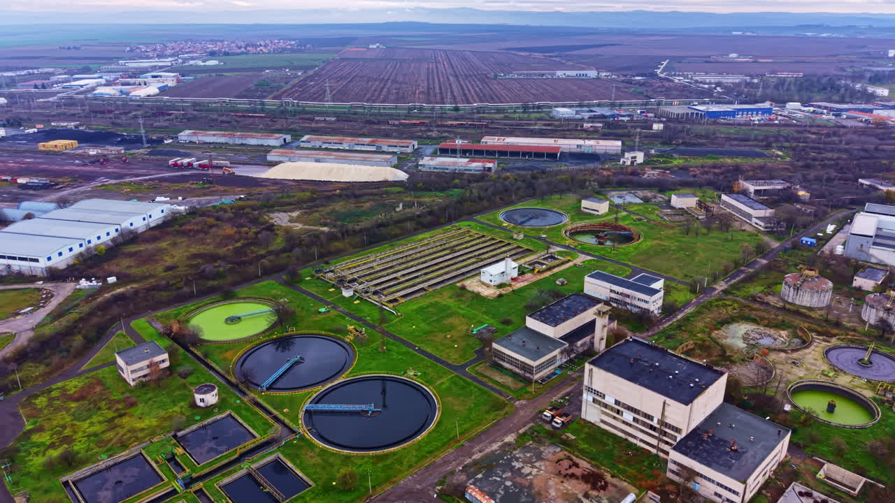 Water treatment facility located near urban areas with multiple tanks and green spaces featuring different water treatment processes and structures in operation during daytime