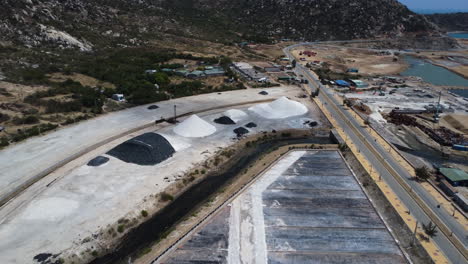 Aerial,-salt-piles-stacked-by-industrial-salt-field-in-Phan-Rang,-Vietnam