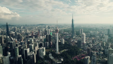 kuala lumpur telecommunication tower with mega tall skyscraper merdeka 118 on the right before sunrise, southeast asia, panoramic drone view