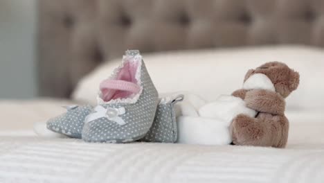 baby shoes and teddy bear on bed