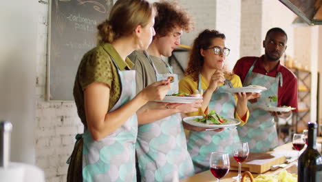 varios amigos comiendo ensaladas durante la clase de cocina