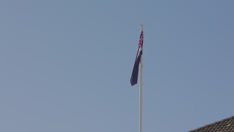 the australian flag blows patriotically in the wind against a clear blue sky background in sydney australia