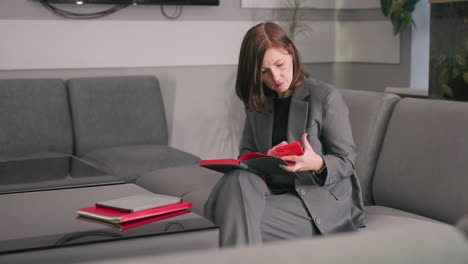 businesswoman writing in notebook during break in modern office, working, focused, planning, organizing, professional attire, corporate environment, productivity, work-life balance