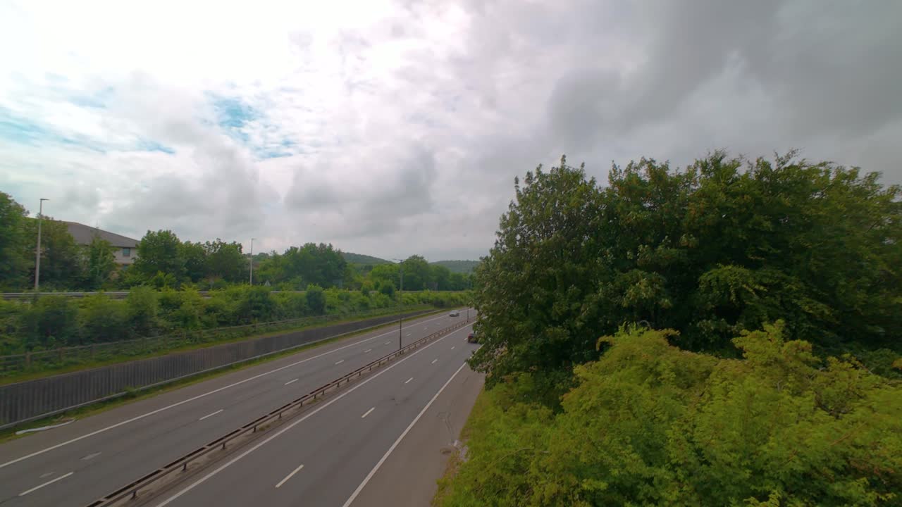 Moving Hyperlapse of Motion Blur Cars Zooming Fast Down Motorway Road with Trees and Quickly Moving Clouds Overhead. Dual Carriage Flowing Traffic