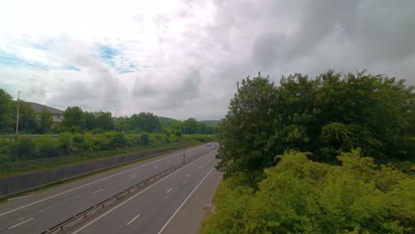 moving hyperlapse of motion blur cars zooming fast down motorway road with trees and quickly moving clouds overhead. dual carriage flowing traffic