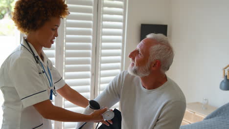 Female-Nurse-Wearing-Uniform-Taking-Blood-Pressure-Of-Senior-Man-In-Private-Hospital-Room