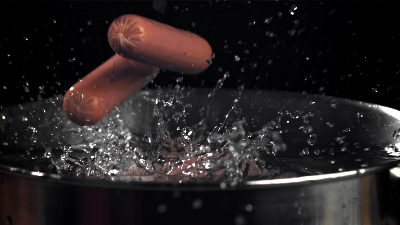 Hotdogs falder ned i vand med plask i slow motion.