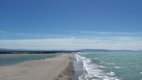 aerial ascent above 'finger' of land towards meeting of river and sea on a beautiful spring day - ashley river mouth and pegasus bay, new zealand