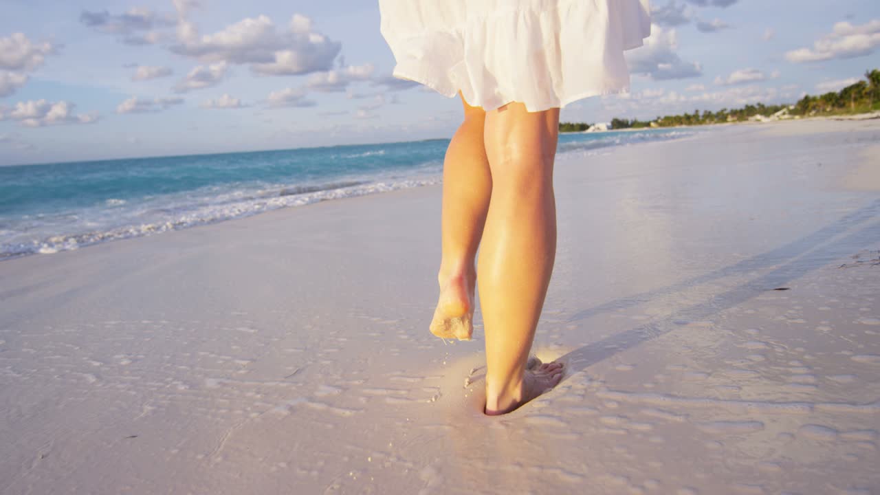 Donna caucasica a piedi nudi sulla spiaggia al tramonto