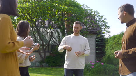 caucasian young man teaching his friends how to throw petanque balls to start the game