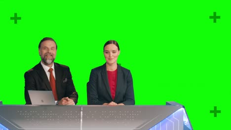 green screen background: live news studio with beautiful female and handsome male anchors reporting on the events of the day. television channel newsroom concept.chroma key background tracking markers