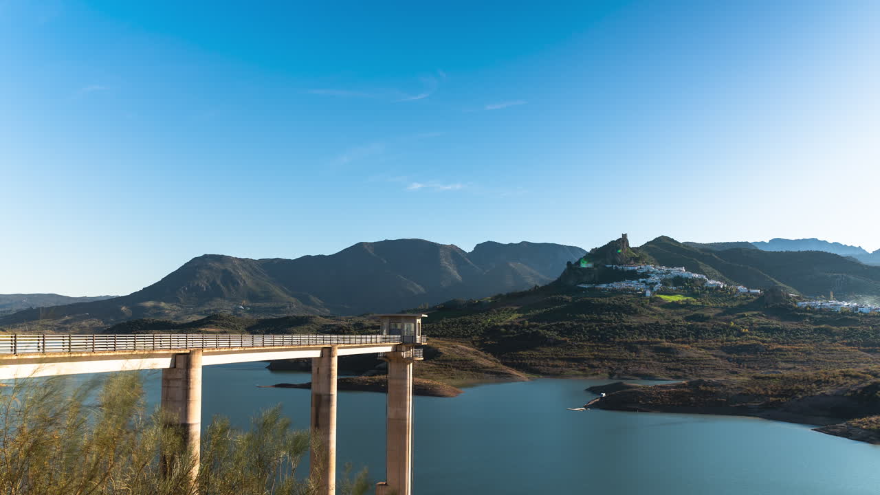 Timelapse, Zahara-El Gastor Reservoir in Spain. Small Castle village is in the distance. Beautiful blue skies, calm lake.