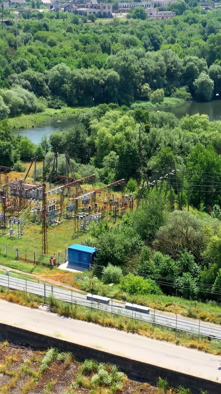 Modern solar power farm among beautiful summer nature. Blue solar panels on the bank of the river. Production of clean energy. Aerial shot. Vertical video