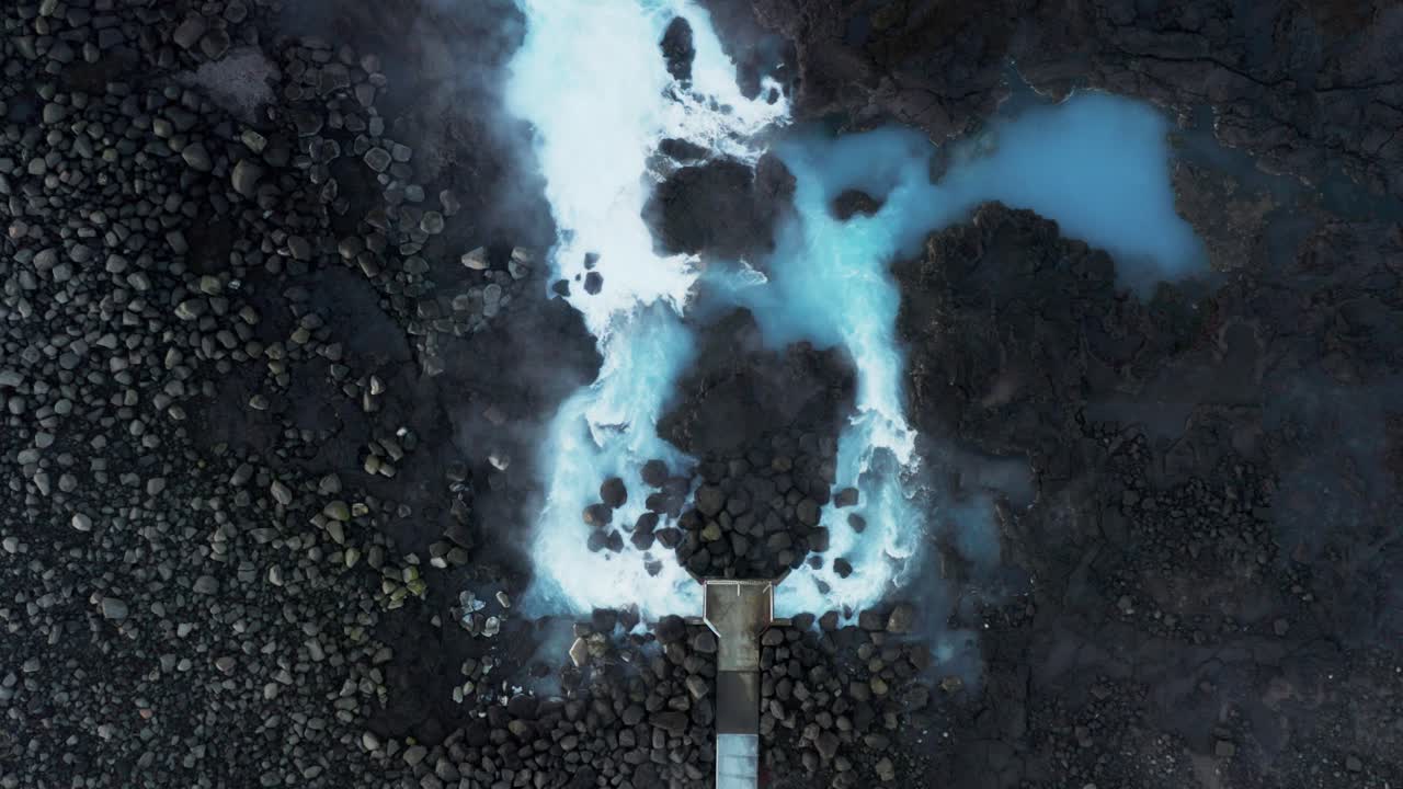 agua humeante azul lechoso que fluye de la tubería en la costa volcánica, islandia