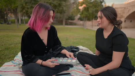 two women discussing makeup in a park