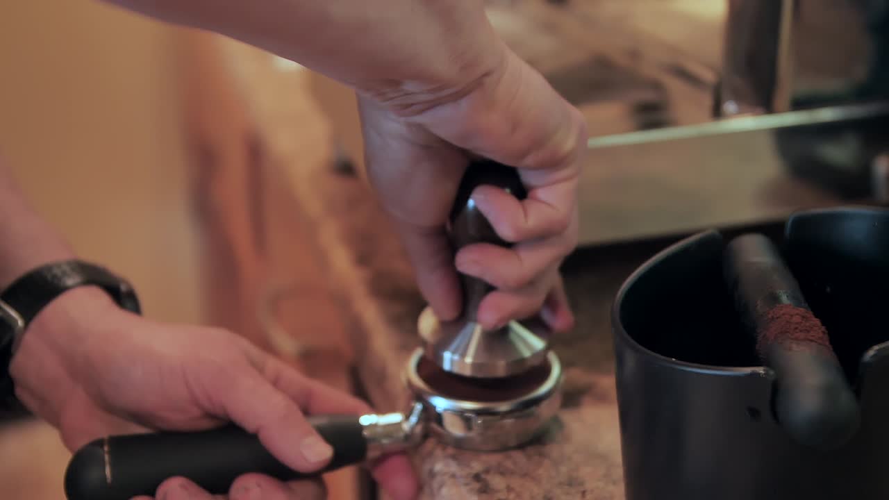 Usando um porta-filtro para fazer uma xícara de café expresso, close-up em câmera lenta.