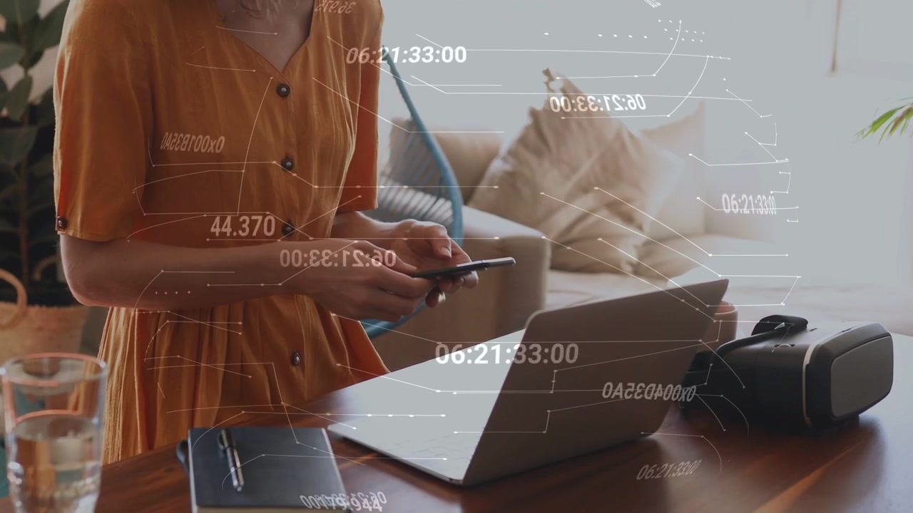 Kvinna som skriver på laptop och skapar datadiagram, tar upp telefonen och synkroniserar med laptopen för teknik.