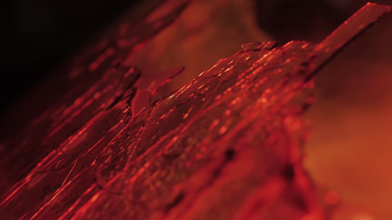 Slow motion close-up of a shattered windshield of a completely burnt car, with a shallow depth of field