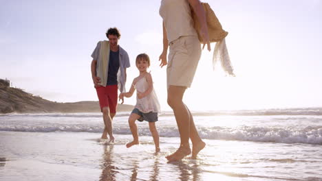 Happy-family-playing-in-the-waves-on-the-beach-at-sunset-on-vacation