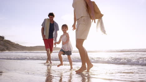 happy family playing in the waves on the beach at sunset on vacation