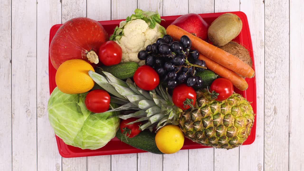 Fruits and vegetables move in red tray on light wooden theme. Stop motion