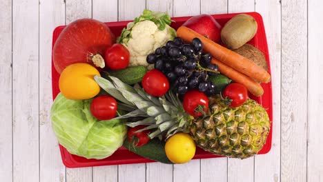 fruits and vegetables move in red tray on light wooden theme. stop motion