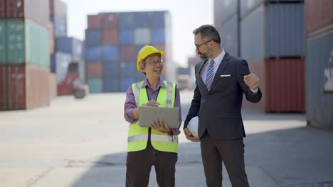 gerente o inversor e ingeniero senior se reúnen y discuten sobre el proceso de carga de carga y el proceso de envío o hablan en detalle del nuevo proyecto en el plan de negocios en la computadora portátil en el patio de contenedores de carga.