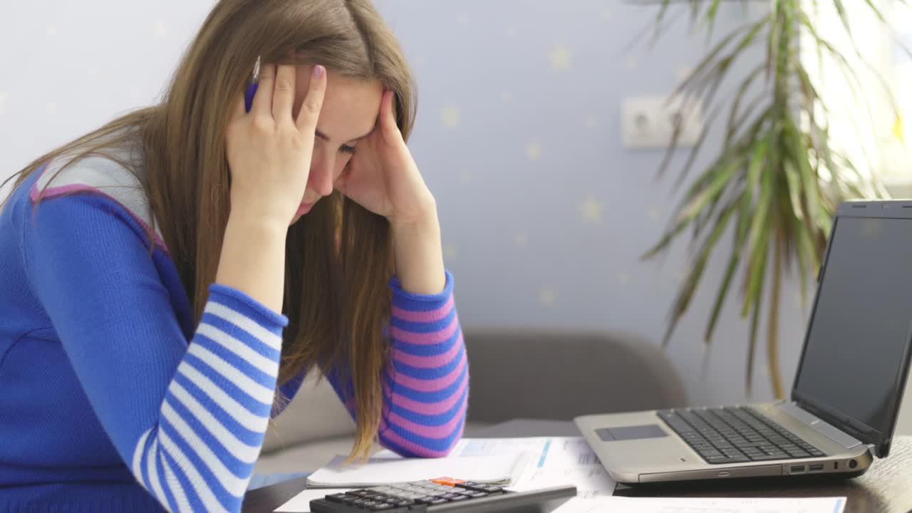 Stressed young brunet woman sits at home manage household finances frustrated with family financial problems. Distressed upset female disappointed with money debt, pays bills taxes online on laptop