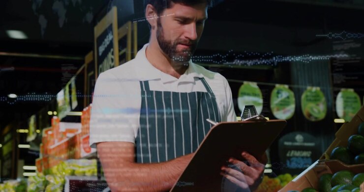La telecamera si allarga, addetto al reparto ortofrutta che controlla gli avocado scrivendo le scorte su un blocco con una penna, sovrapposizioni che si incrociano sul blocco