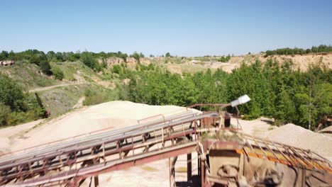 montones de arena y una cinta transportadora en una antigua cantera de arena cerca de la ciudad de prudnik, polonia - avión no tripulado volando hacia adelante