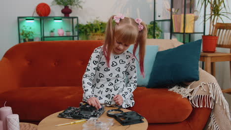 Little-girl-kid-fixing-repairing-computer-mainboard-technology-part,-using-magnifying-glass-at-home