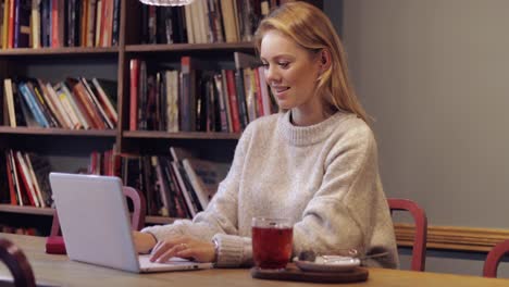 Frau-Im-Pullover-Mit-Laptop-In-Bibliothek