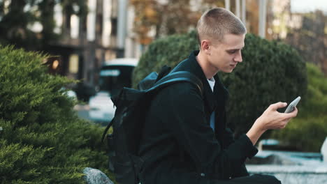 young student using mobile phone outdoors.