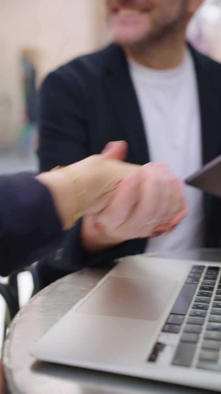 Primo piano di una donna d'affari che digita su un laptop e poi dà il cinque a un uomo d'affari che tiene un tablet per celebrare un accordo.