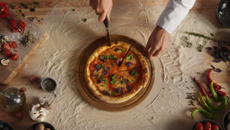 professional chef slicing pizza by round cutter knife in restaurant kitchen.