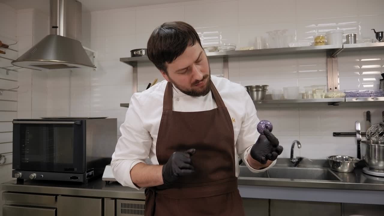 un chef de pastelería tiene un caramelo de chocolate hecho a mano o praline en una pastelería.