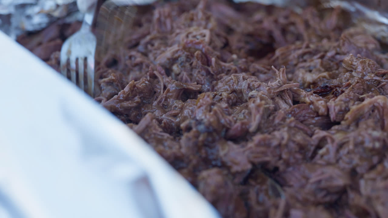 Extreme Close up, Hand Held, A large tray with Beef Brisket which is pulled and shredded with two forks