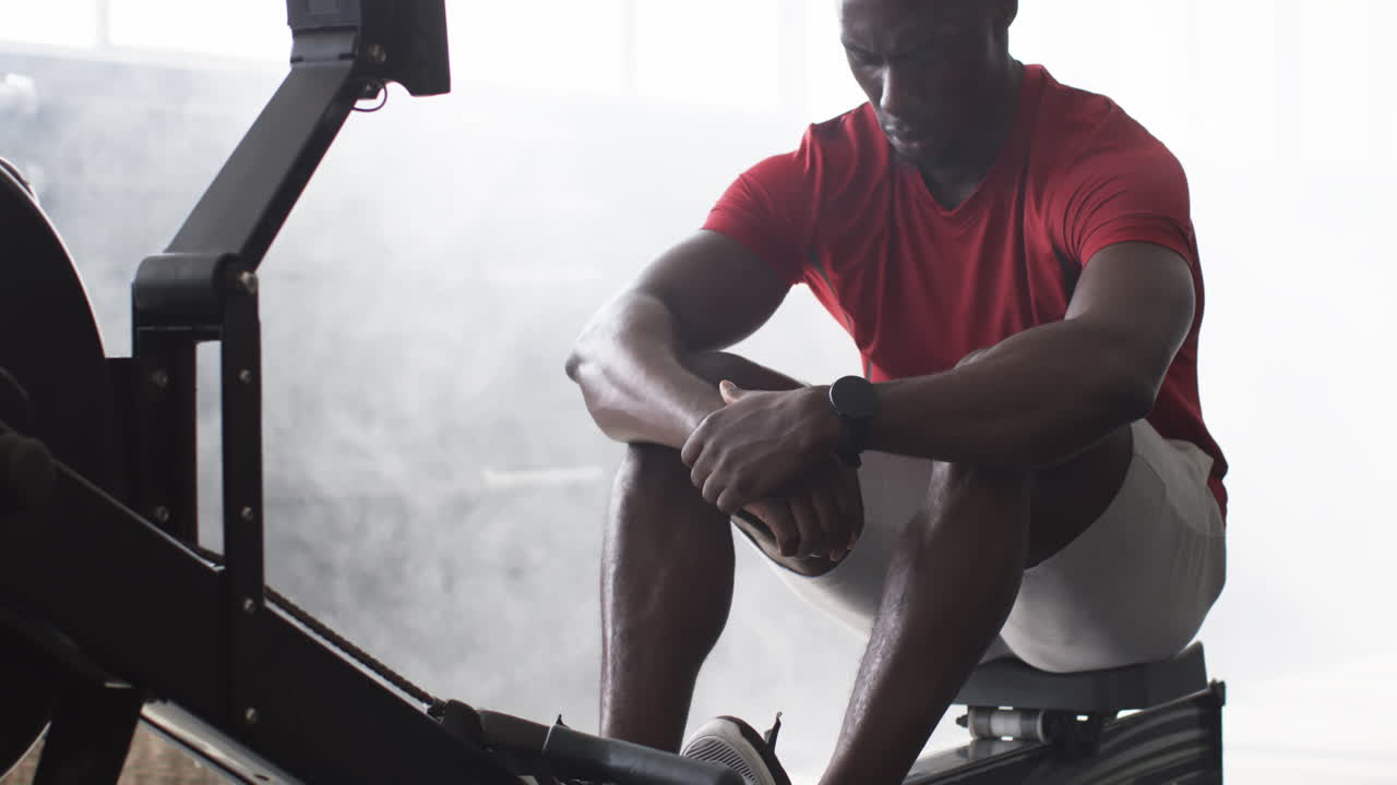 Resting after intense workout, man in gym sitting on exercise machine