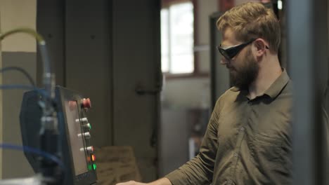 the worker presses buttons of the panel of the machine tool with numerical programmed control. the engineer configures a program for operation of the cnc machine.