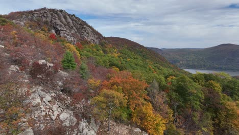 An-aerial-view-over-the-mountains-in-upstate-NY-during-the-fall-foliage-change,-on-a-beautiful-day-with-white-clouds