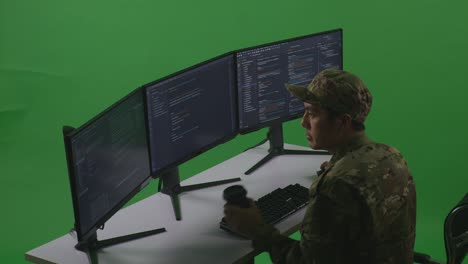 side view of asian man soldier developer drinking coffee and using computer to write code with multiple screens in green screen studio